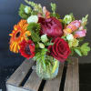 Mixed bouquet in a clear glass vase with red, orange, pink, and white blooms