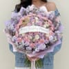 Large pastel bouquet of roses, carnations, and lilac flowers with a birthday ribbon