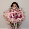 Woman holding a large pink bouquet of roses with a ribbon bow