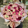 Large bouquet of pink, blush, and burgundy roses wrapped in paper