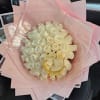 Bouquet of white roses wrapped in pink paper with a gold handle