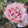 Large bouquet of pink, lavender, and white roses wrapped in pink paper