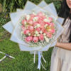 Bouquet of pink and white roses wrapped in white paper