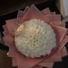 Round bouquet of white roses with a jeweled crown on pink wrapping