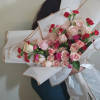 Bouquet of pink roses and red carnations wrapped in white paper