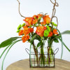 Orange roses in glass bottles with curly branches and green accents