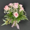 Pink roses in a glass vase with baby's breath and greenery