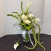 White calla lilies and roses in a glass vase with a matching boutonniere