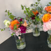 Three mixed floral bouquets in clear glass vases on a black table