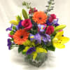 Colorful bouquet of roses, lilies, and gerbera daisies in a glass vase