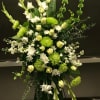 Tall green and white standing spray with roses, mums, and bells of Ireland on a metal easel