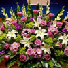Large altar arrangement of white lilies, pink roses, and pink daisies with green and purple accents.