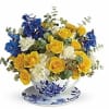 Yellow and blue roses arranged in a teacup with matching saucer