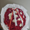 Round bouquet of red and white roses wrapped in white paper with a ribbon