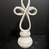 White decorative cross on a carved pedestal base