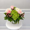 Pink roses and white hydrangeas in a glass vase with green filler