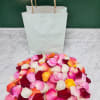 Pile of multicolored rose petals in front of white paper bags