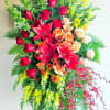 Large standing floral spray with red roses, lilies, and yellow blooms