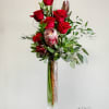 Tall vase arrangement of red roses with greenery and a protea