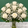 White roses and baby's breath in a clear glass vase