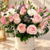 Pink roses and carnations arranged in a white hat box