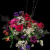 Bouquet of red roses, purple blooms, and white baby's breath in a glass vase