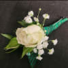 White rose boutonniere with baby's breath and green ribbon wrap