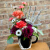 Colorful flower arrangement in a black mug with a skeletal hand decoration
