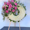 Heart-shaped floral wreath with pink roses and white chrysanthemums on an easel