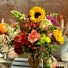 Mixed bouquet with sunflowers, carnations, and alstroemeria in a glass vase