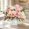 Pink and cream rose arrangement in a patterned white vase