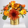 Orange and yellow floral arrangement in a gold vase
