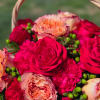 Bouquet of pink and peach roses with carnations in a basket