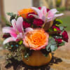 Pink lilies and orange roses in a pumpkin-shaped vase
