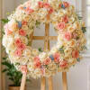 Heart-shaped wreath of cream and peach roses on a wooden easel