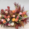 Autumn floral arrangement in a wicker basket with orange and pink blooms
