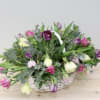 Basket of pink, purple, and white tulips with greenery
