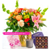 Mixed bouquet with orange roses, pink lilies, and carnations with card, candle, and chocolates.