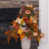 Tall autumn floral arrangement in a white pedestal vase