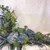 Blue and green floral arrangement with hydrangeas and tall spiky blooms