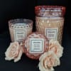 Three rose-scented candles with pale pink roses on a black background