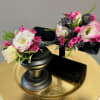 Two small floral arrangements on black stands with pink and white blooms