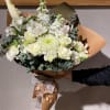 White bouquet with roses, lilies, and chrysanthemums wrapped in brown paper