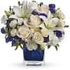White roses and lilies arranged in a blue glass vase