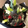 Bouquet of red roses and white lilies wrapped in black paper