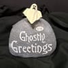 Ghost figurine on a gray stone with "Ghostly Greetings" text