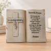 Decorative memorial plaque shaped like an open book with a cross and prayer text