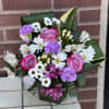 Bouquet of pink roses, white daisies, and purple carnations in a vase