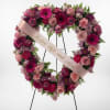 Heart-shaped floral wreath with pink and purple flowers and a ribbon