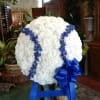 Large white floral standing spray with blue ribbon and blue accents